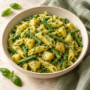 AI illustration of basil pesto pasta with potato cubes and green beans.