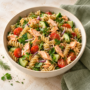 AI illustration of salmon flakes with brown rice pasta, cucumber and tomatoes.