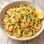AI illustration of spaghetti with shrimp, garlic, lemon zest and parsley in a light olive-oil sauce.
